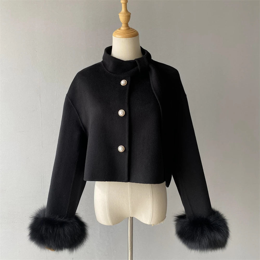 Black coat with fur cuffs on a mannequin against a plain background