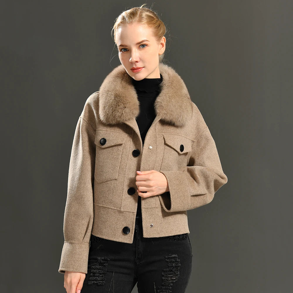 Woman wearing a beige coat with a fur collar against a gray background