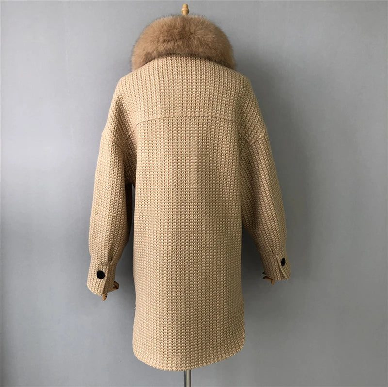 Beige knitted coat with fur hood on a mannequin against a gray background