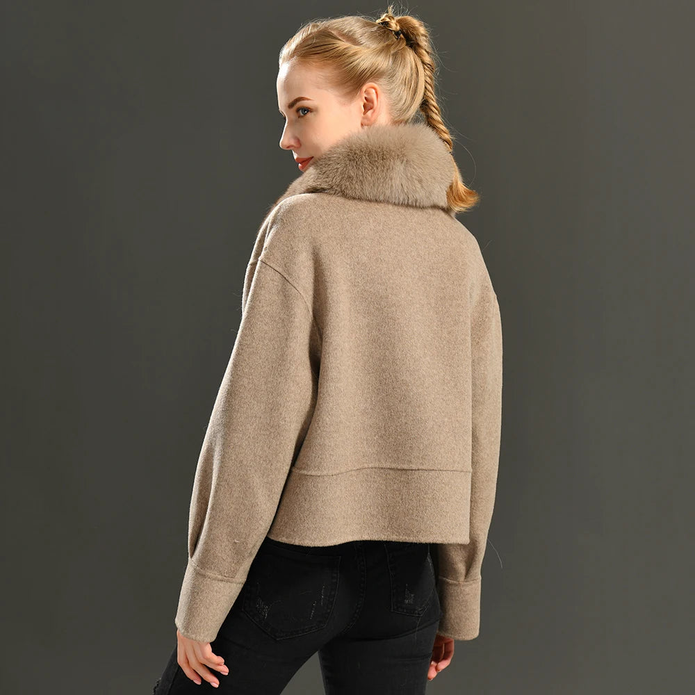 Woman wearing a beige coat with a fur collar against a dark background