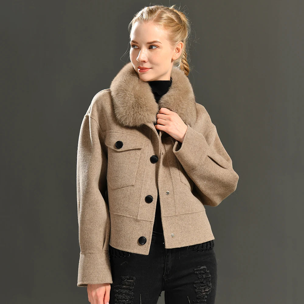 Woman wearing a beige coat with a fur collar against a gray background