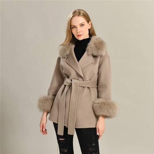 Woman wearing a beige coat with fur accents on a plain background