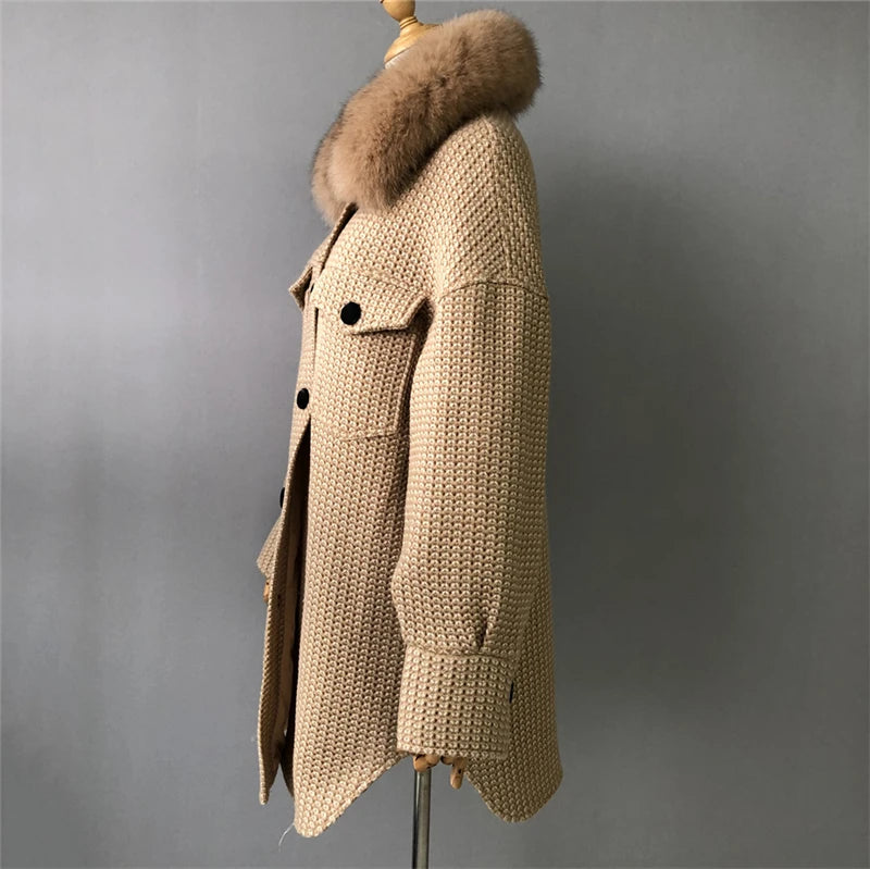 Beige knitted coat with fur hood on a mannequin against a gray background