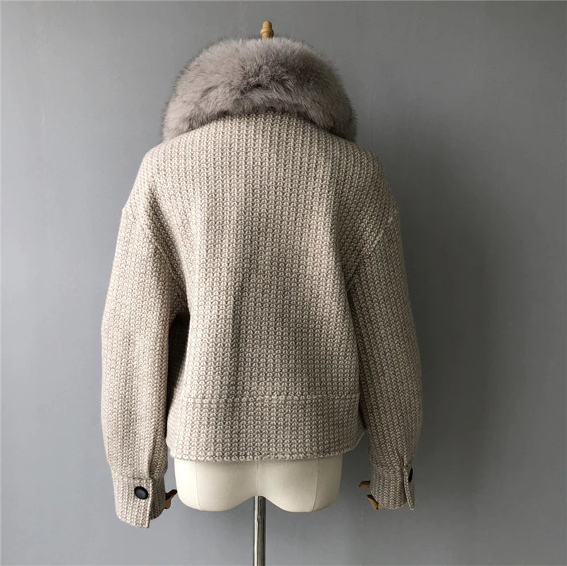 Beige knitted jacket with fur hood on a mannequin against a gray background