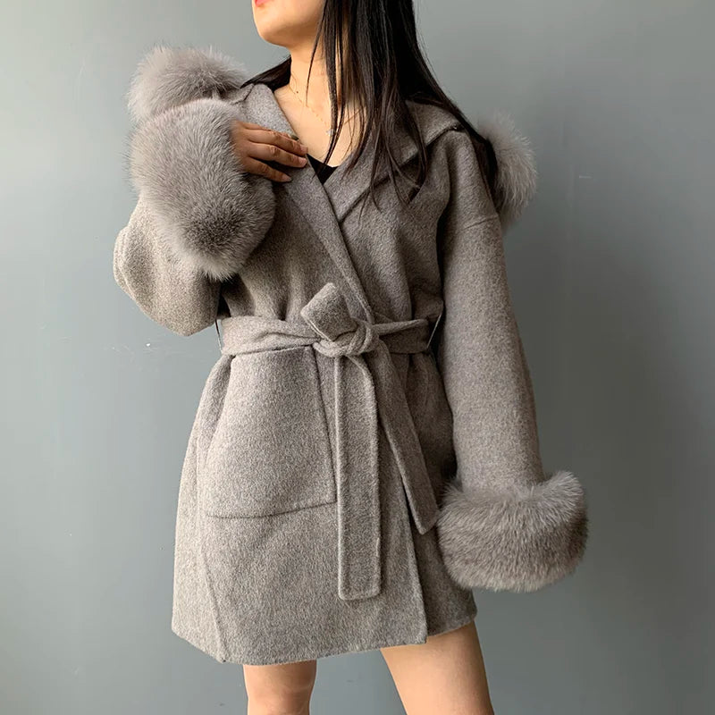 Gray coat with fur cuffs worn by a person on a gray background