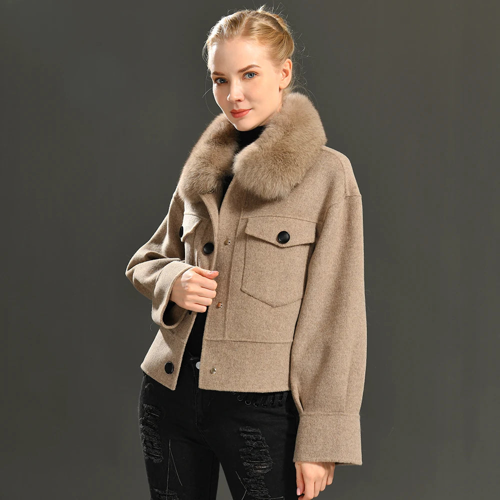 Woman wearing a beige coat with a fur collar against a dark background
