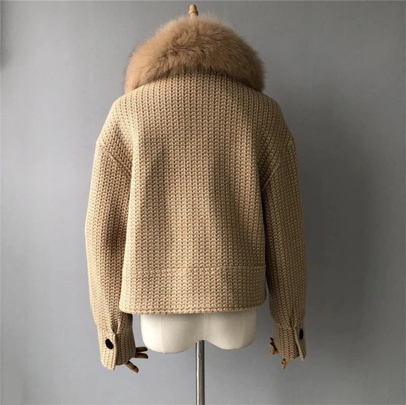 Beige knitted sweater with fur hood on a mannequin against a gray background