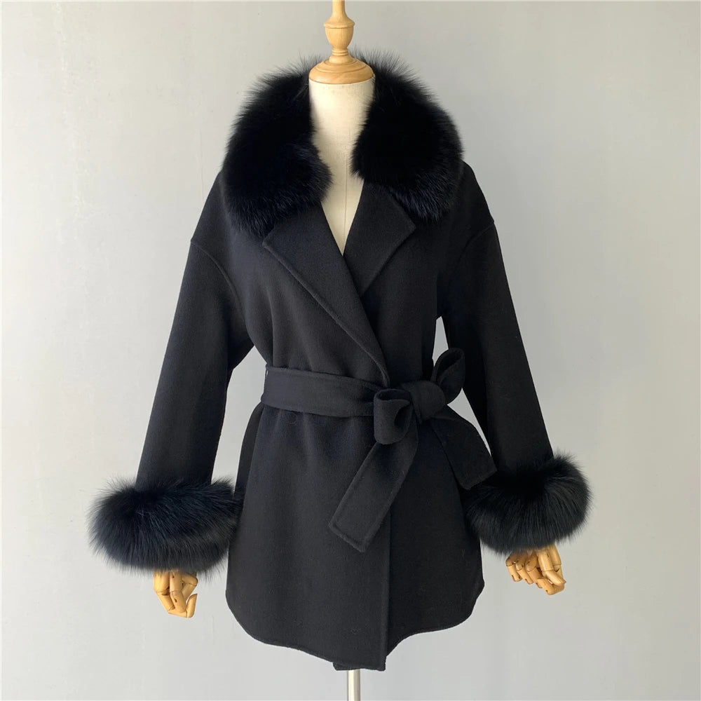 Black coat with fur trim on a mannequin against a plain background