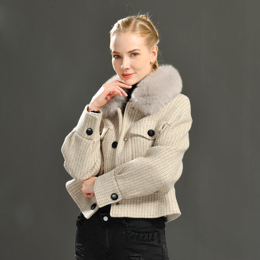Woman wearing a beige knitted jacket with fur collar against a dark background