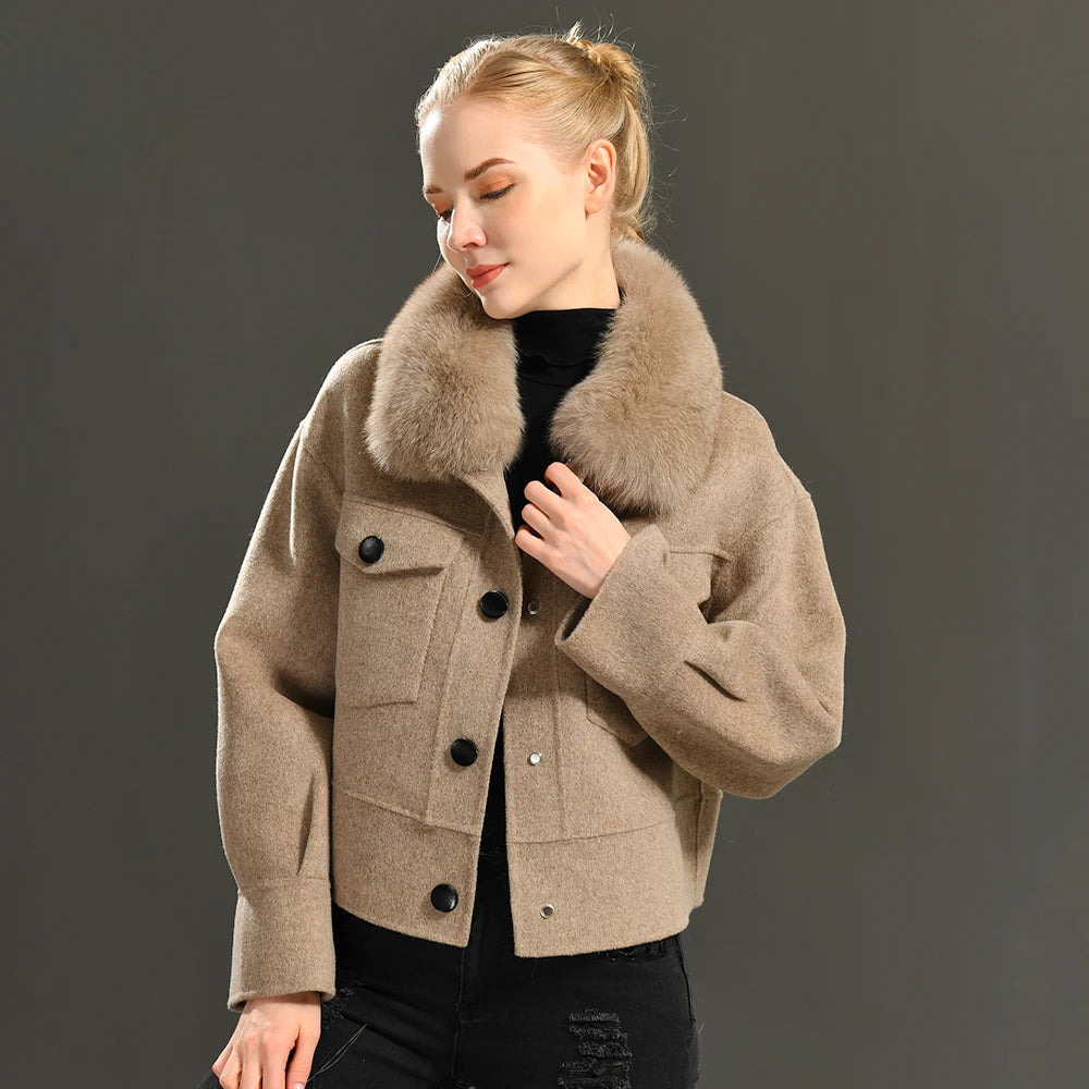 Woman wearing a beige coat with a fur collar against a dark background