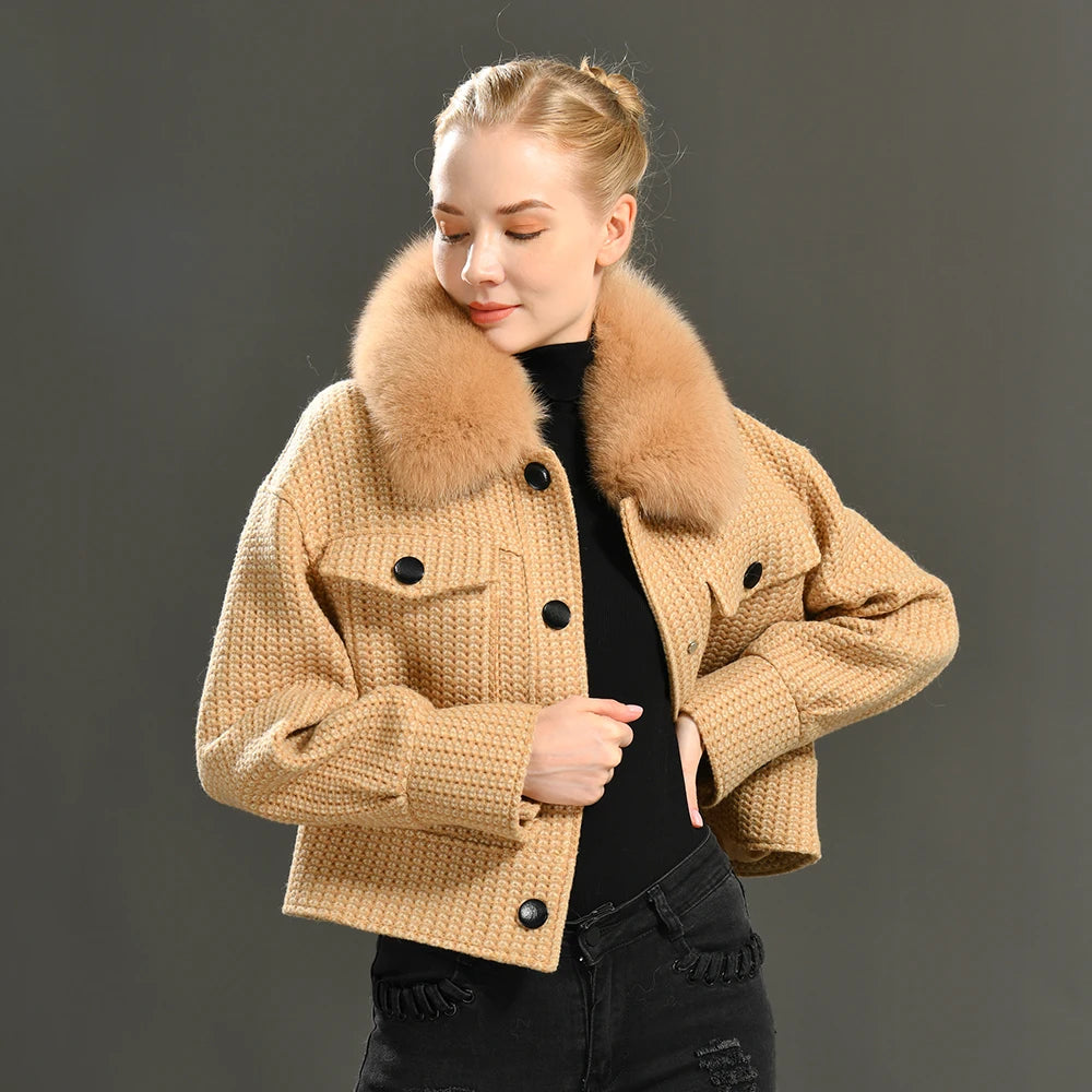 Woman wearing a beige knitted jacket with a fur collar against a dark background