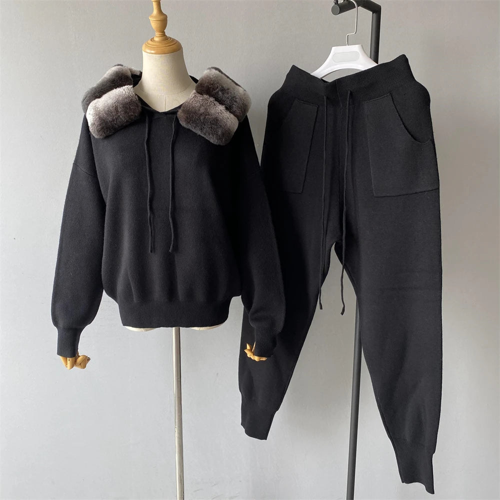 Black hoodie with fur collar and matching pants on a mannequin and hanger against a plain background.