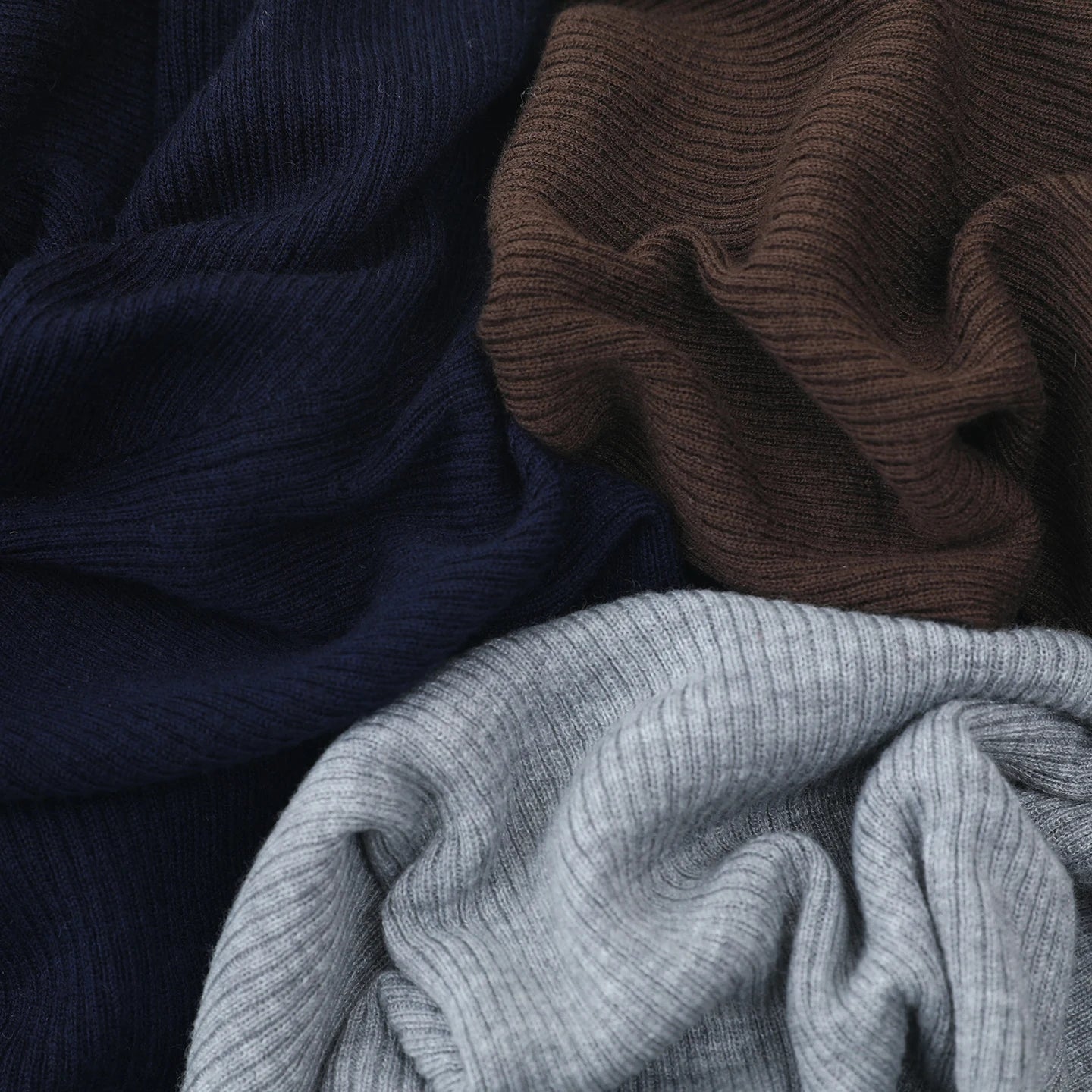 Close-up of folded navy, brown, and gray ribbed fabric.