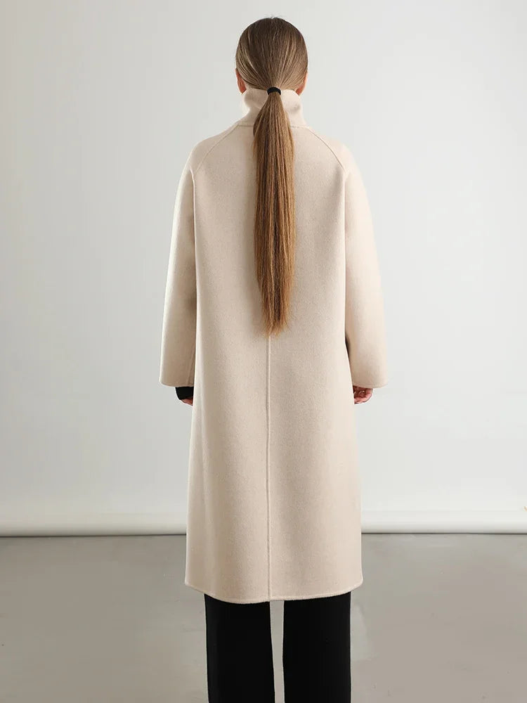 Person wearing a beige coat with a plain background