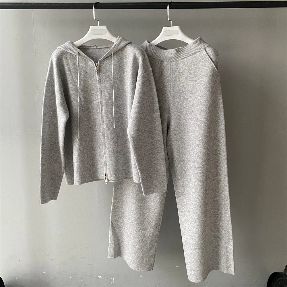 Gray hoodie and pants set on hangers against a plain background