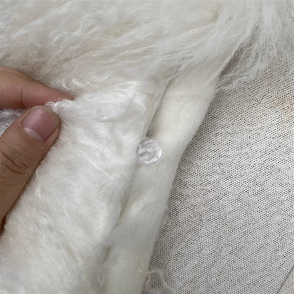 Close-up of white fluffy material with a hand touching it, on a neutral background.