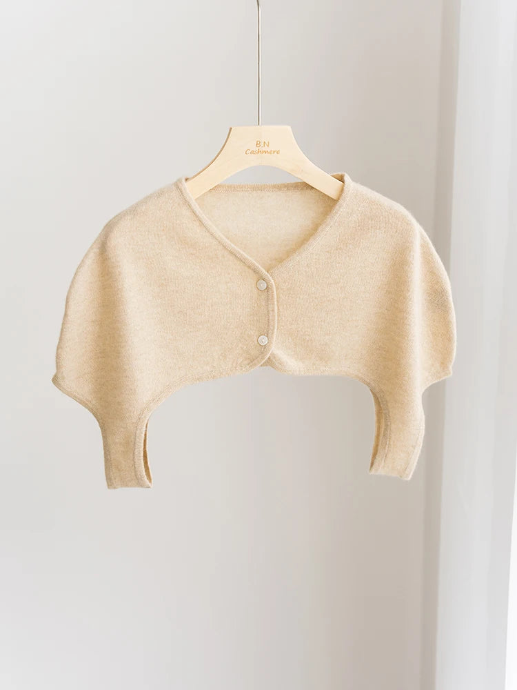 Beige cardigan on a wooden hanger against a light gray background