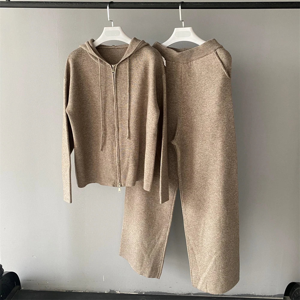 Beige hoodie and pants set hanging on a rack against a plain background