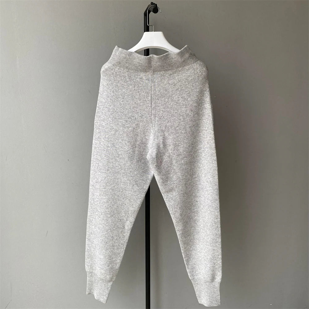 Gray pants on a hanger against a plain background