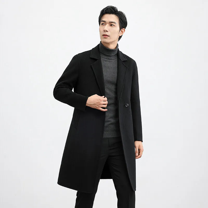 Man wearing a black coat over a gray sweater on a white background