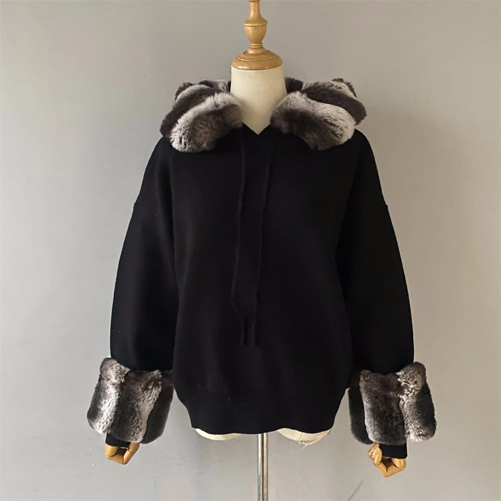 Black coat with fur trim on a mannequin against a plain background