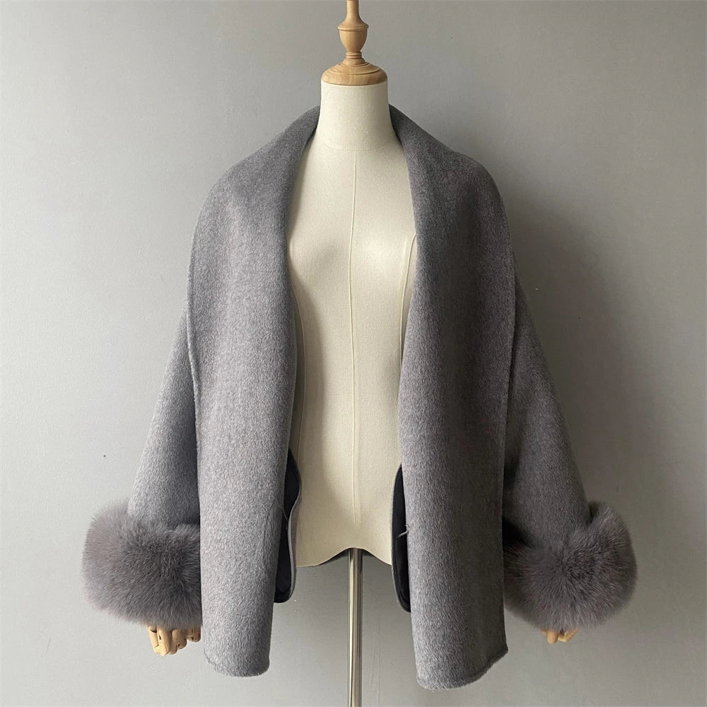 Gray shawl with fur trim on a mannequin against a plain background