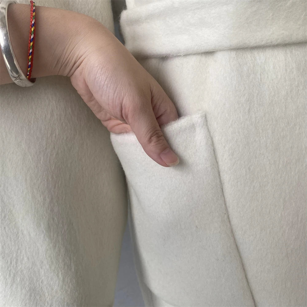 Hand with a bracelet touching a white fabric surface