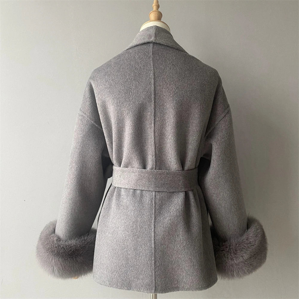 Gray coat with fur cuffs on a mannequin against a plain background