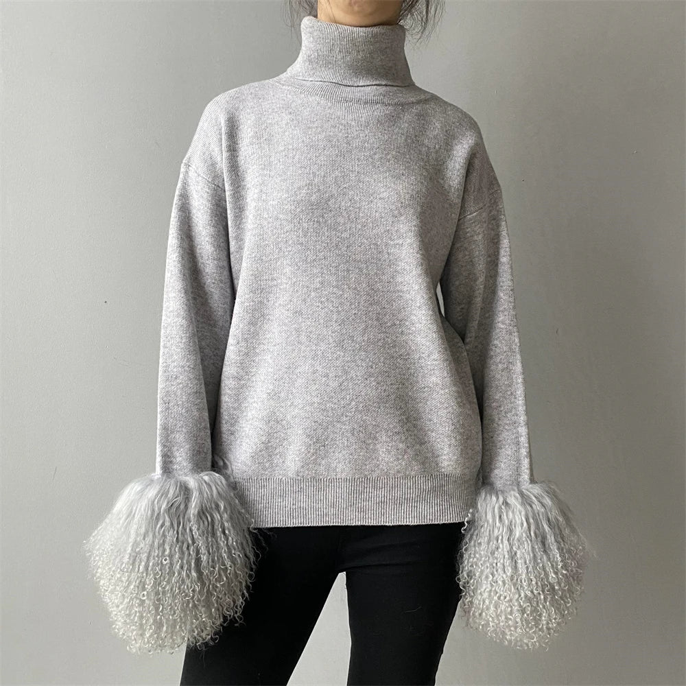 Gray sweater with fluffy cuffs worn by a person on a plain background