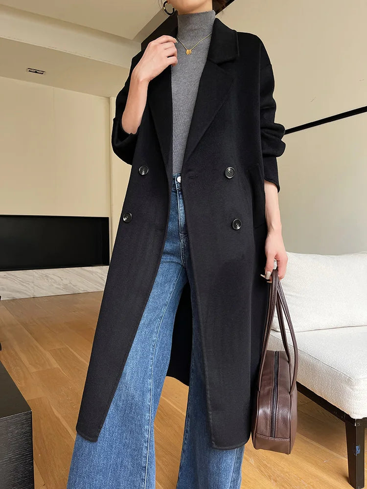 Person wearing a black coat and blue jeans indoors.