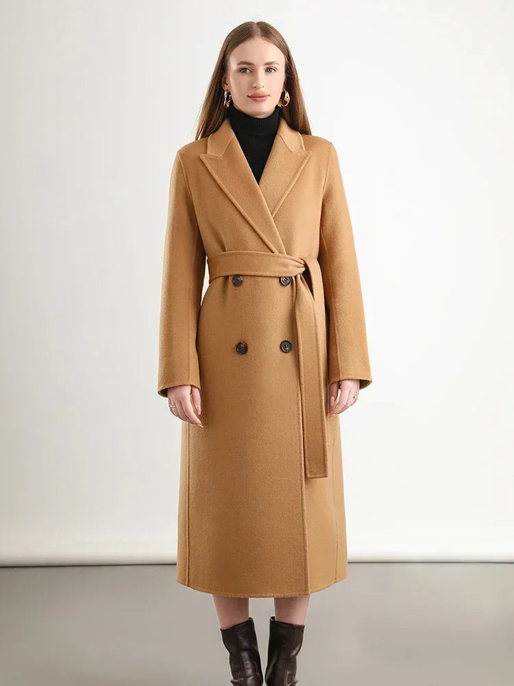 Woman wearing a tan coat with a belt on a plain background