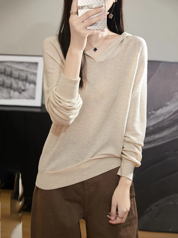 Person wearing a beige sweater and brown pants in an indoor setting.