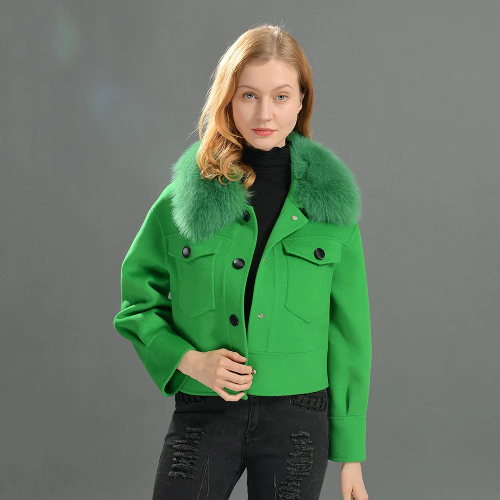 Woman wearing a green jacket with fur collar against a gray background