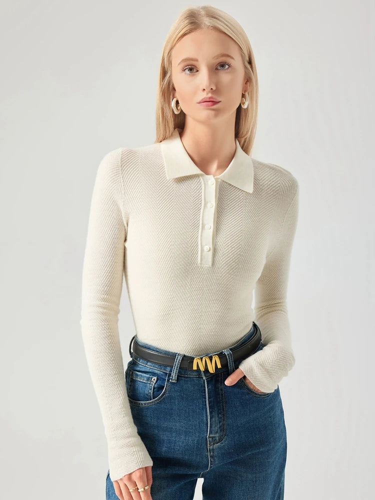 Woman wearing a cream long-sleeve polo shirt and blue jeans on a light gray background