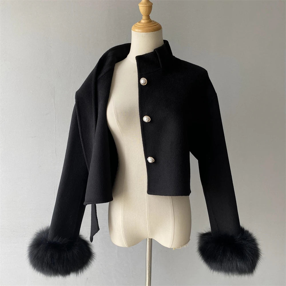 Black jacket with fur cuffs on a mannequin against a plain background