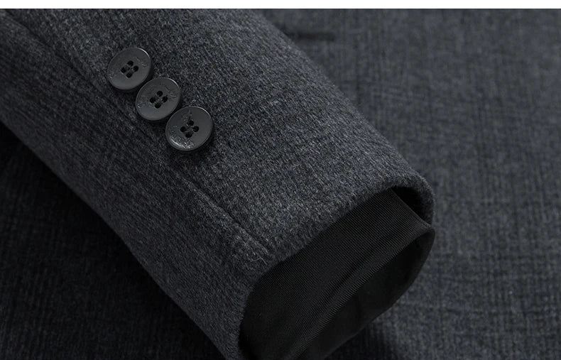 Close-up of a dark gray coat with buttoned sleeve cuffs on a matching fabric background.