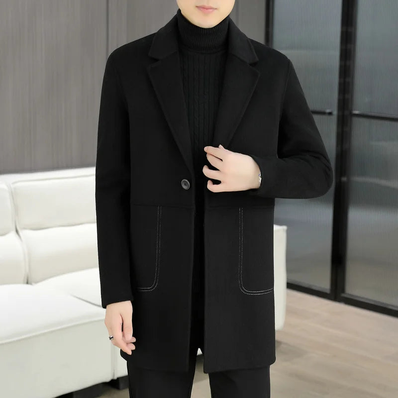 Person wearing a black coat in an indoor setting with a white couch and glass door.