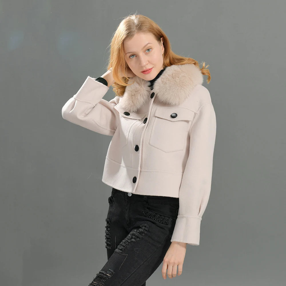 Woman wearing a light-colored jacket with fur collar against a gray background