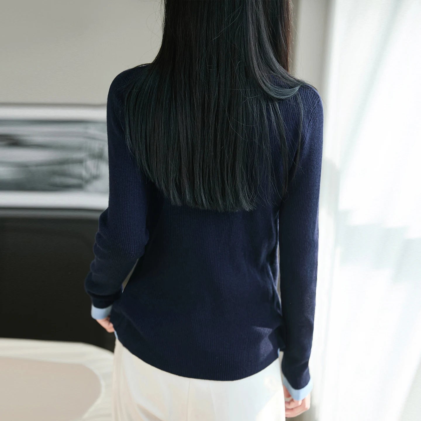 Person wearing a navy sweater with a blurred background