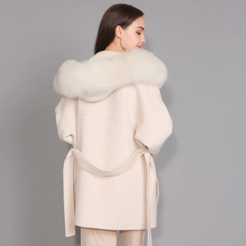 Woman wearing a cream-colored coat with a fur collar against a gray background