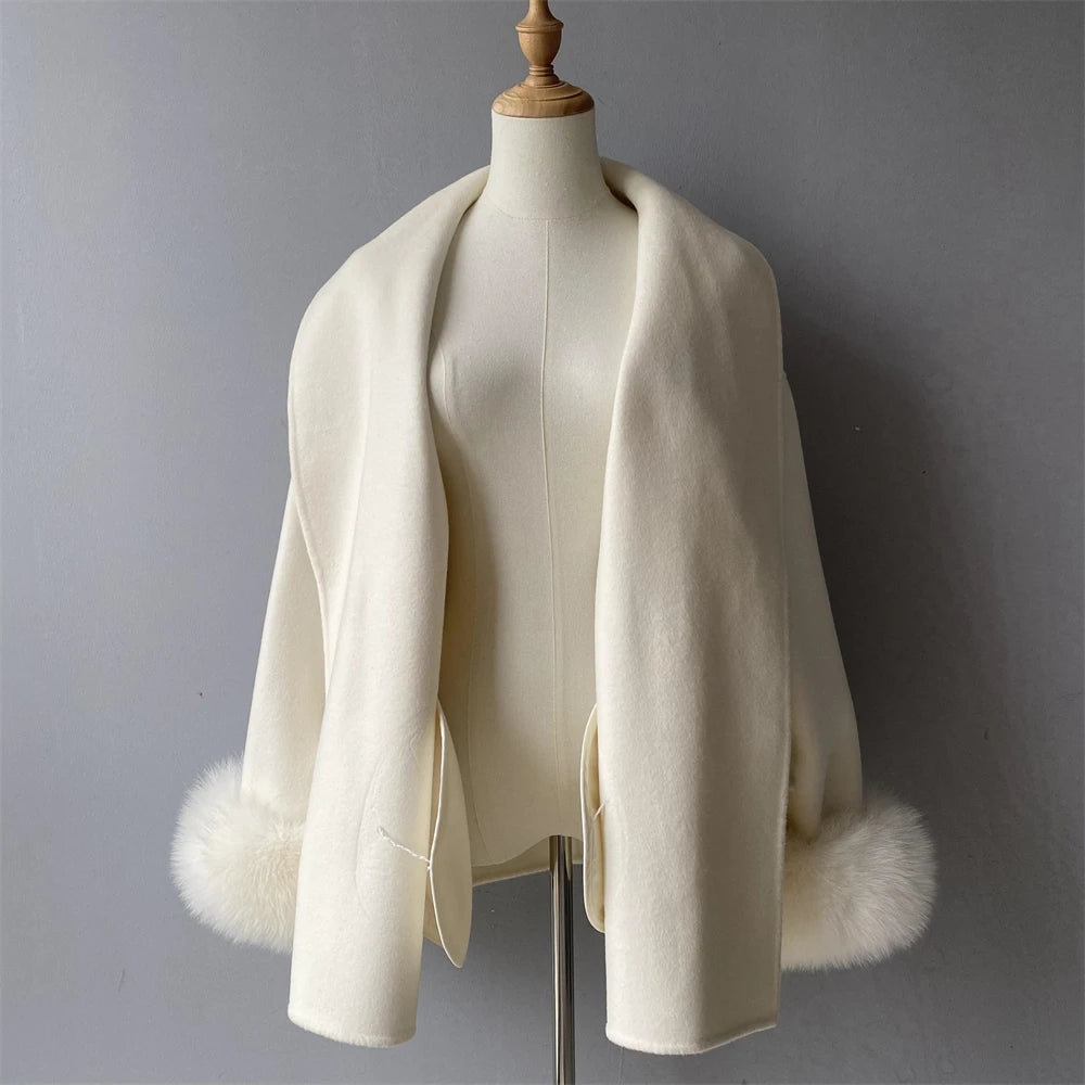 White shawl with fur trim on a mannequin against a gray background