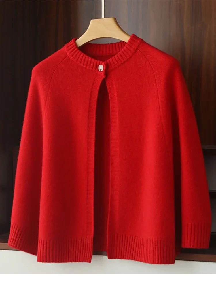 Red knitted cardigan on a wooden hanger against a dark background