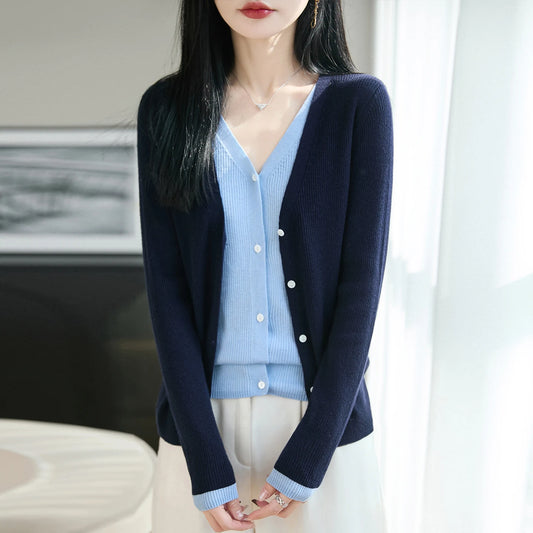 Woman wearing a navy cardigan over a light blue shirt with white pants.