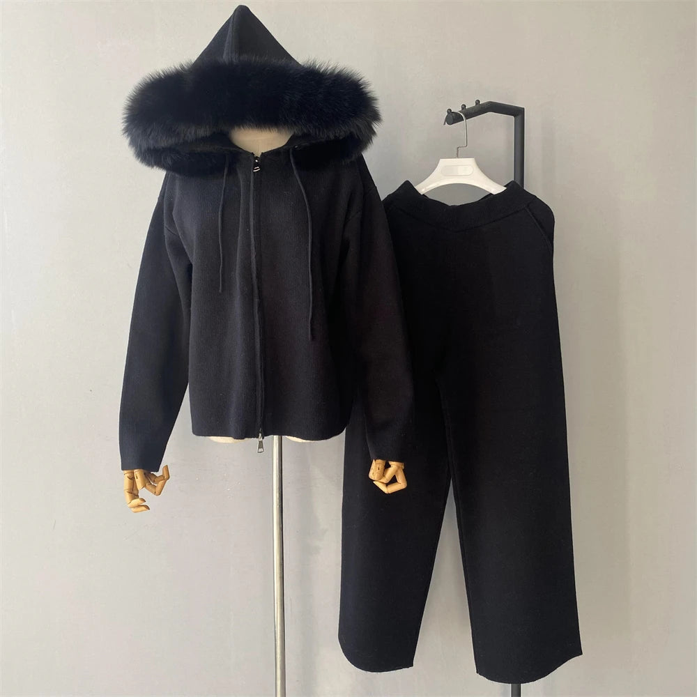 Black hooded jacket with fur trim and matching pants on a mannequin against a plain background.