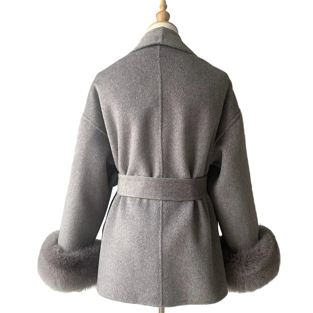 Gray coat with fur cuffs on a mannequin against a plain background