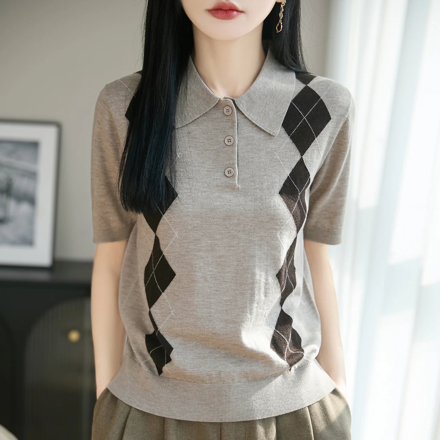 Person wearing a gray argyle patterned shirt with a blurred background