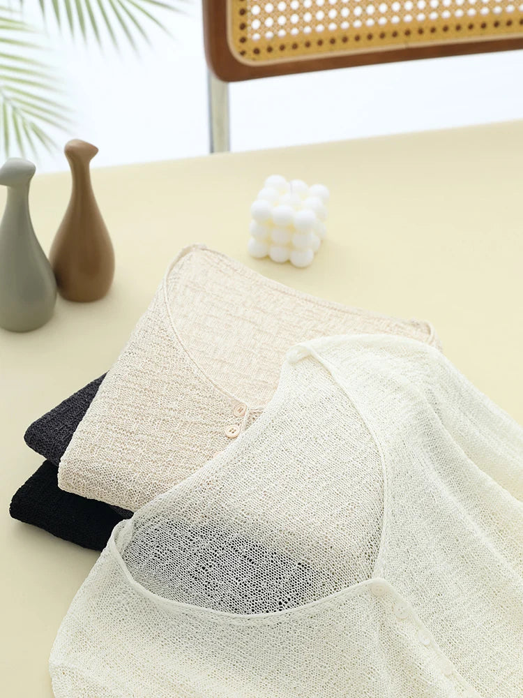 Three lace-trimmed undergarments in black, white, and beige on a light surface with decorative items.