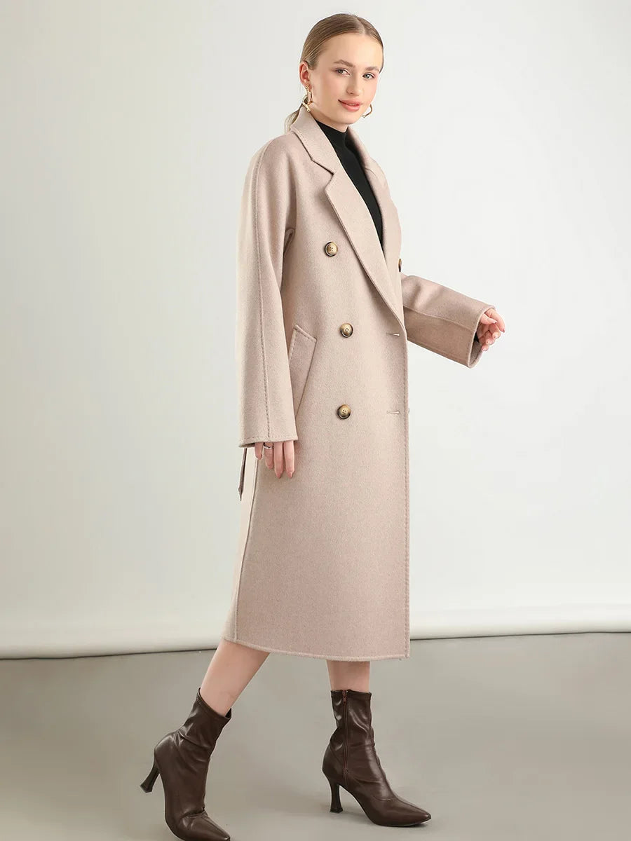Woman wearing a beige coat with gold buttons on a plain background
