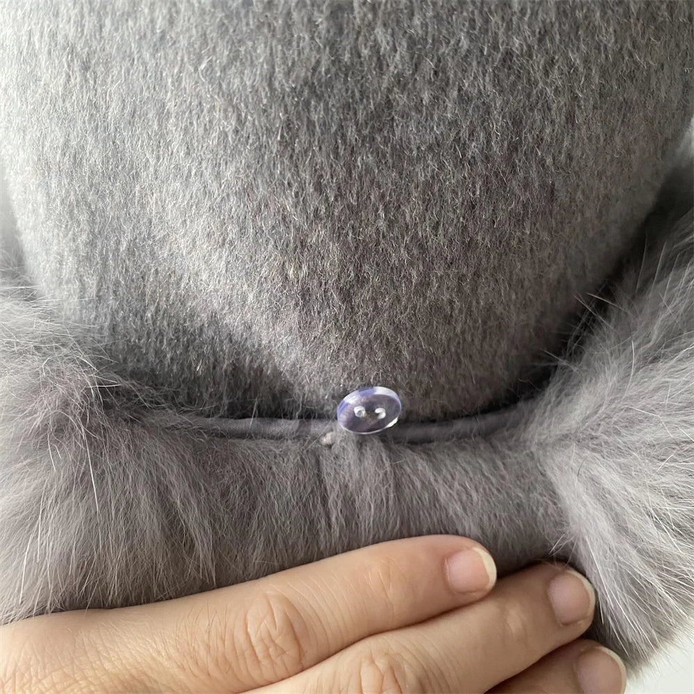 Close-up of a gray fur coat with a button and a hand touching it