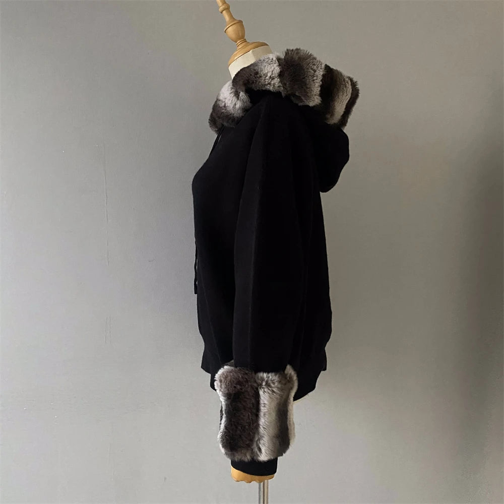 Black coat with fur trim on a mannequin against a plain background
